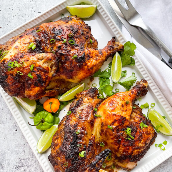 Lemon Garlic Chicken Thighs in a tray with some lemon wedges